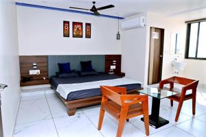 a bedroom with a bed and a table and a chair at hotel cloud 20 in Jambusar