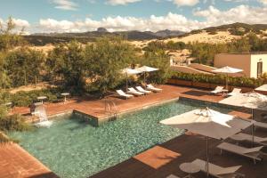 una piscina con sombrillas y sillas y una piscina en Hotel Le Dune Piscinas, en Ingurtosu