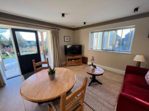 a living room with a table and a tv at Award Winning Lodge at Ewen Barn, Ewen, Cirencester in Cirencester