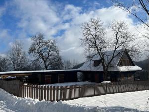 a house covered in snow with a fence at Chalupa u Golisov in Zákopčie