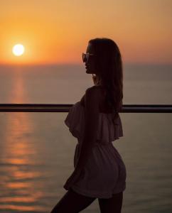 una mujer parada frente al océano al atardecer en ORBI CITY grand first line sea view, en Batumi