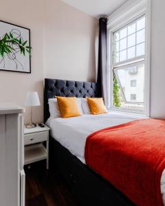 a bedroom with a bed with orange pillows and a window at The Regency | Seafront Lux Apartments! in Southend-on-Sea