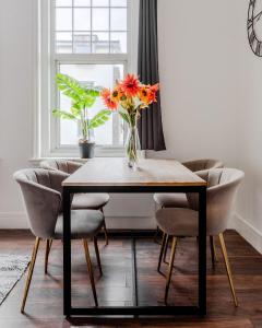 a dining room table with chairs and a vase of flowers at The Regency | Seafront Lux Apartments! in Southend-on-Sea