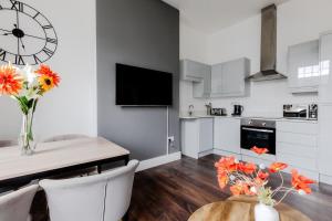 a kitchen with a table and a clock on the wall at The Regency | Seafront Lux Apartments! in Southend-on-Sea