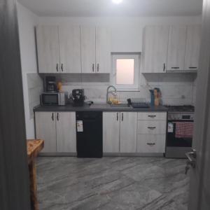a kitchen with white cabinets and black appliances at Casa Ardelean in Sita Buzăului