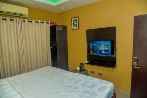 a bedroom with a bed and a flat screen tv at Triple Tee Hotel in Lagos