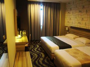 a hotel room with two beds and a desk at Victory City Hotel Crystal Bay in Iskandar Puteri