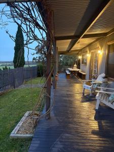 a porch with benches and a table on a house at The Bloom Farm Cottage 