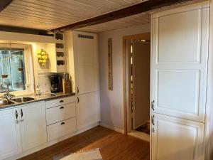 a kitchen with white cabinets and a sink and a door at Dog-friendly cottage with boat & private jetty at Tjörn SE09170 in Krommeröd