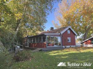a small red house with a porch on a yard at Dog-friendly cottage with boat & private jetty at Tjörn SE09170 in Krommeröd +26 photos