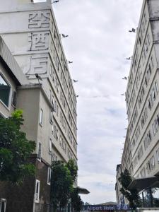Dos edificios altos en una calle de la ciudad con pájaros volando sobre ellos en Lee Airport Hotel 李酒店机场店, en Phrawet