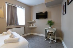 a bedroom with a bed and a desk and a tv at Paragraph Tottenham in Southgate