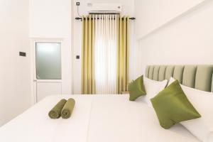 Una cama blanca con dos almohadas verdes encima. en Skyport Villa Katunayaka, en Katunayake