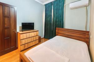 Your Home Inn at Jikia's Green House-Central Tbilisi في تبليسي: غرفة نوم صغيرة بها سرير وتلفزيون