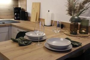 einem Holztisch mit zwei Gläsern und Platten darauf in der Unterkunft Das Atelier im Kalterbach in Bad Laasphe + 7 Fotos