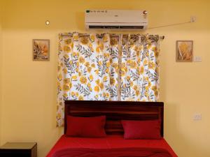 ein Schlafzimmer mit einem Bett mit roten Laken und einem Fenster in der Unterkunft Studio 401 Cityscape Retreat in Deoghar