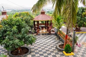 a gazebo in a garden with palm trees at Ambika Hills Resort in Junnar
