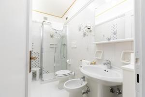 Un baño blanco con inodoro, lavabo y ducha. en Hotel Croce Bianca, en Asiago 35 fotos más