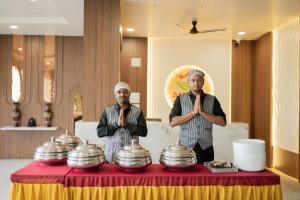 two men are standing in front of a table with prayer bowls at Ambika Hills Resort in Junnar