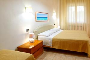 a hotel room with two beds and a table with a lamp at RESIDENCE CERRA in Otranto