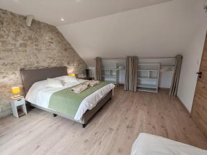 a bedroom with a large bed and a stone wall at Longère de charme rénovée - dépaysement et verdure in Brancourt-en-Laonnois +31 photos