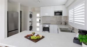 a white kitchen with a plate of fruit on a counter at Coastal Views - waterfront guest apartment in Daleys Point +6 photos