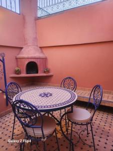 a table and chairs in a room with a fireplace at Riad Izza in Marrakech
