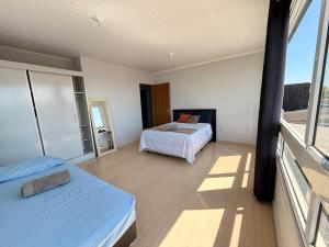 a bedroom with two beds and a large window at Sobrado de 3 quartos in Capão da Canoa
