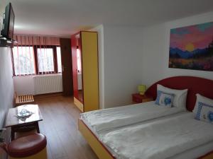 a bedroom with a bed and a table with a chair at Pensiunea Sebastian in Buşteni