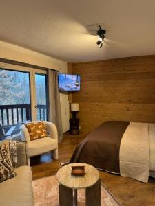 een slaapkamer met een bed, een bank en een tv bij LiHam Alpine Suite in Megève +24 foto's