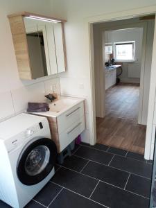 een wasmachine in de badkamer met een spiegel bij Ferienwohnung Nr 2 am Hambach in Falkenbach +9 foto's