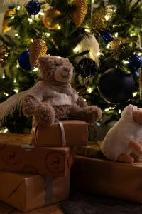 فندق لانكاستر باريس شانزليزيه في باريس: دب تيدي يجلس على الصناديق أمام شجرة عيد الميلاد