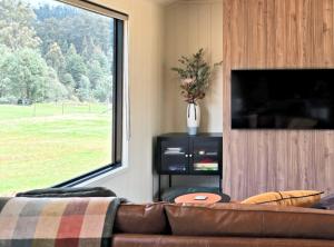 Una sala de estar con un sofá y una ventana grande. en Maydena Alpine Retreat, en Maydena