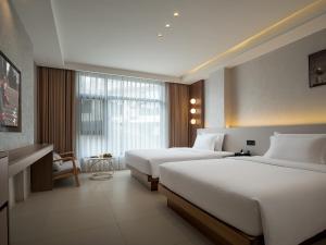 Una habitación de hotel con dos camas y una ventana. en Zhangjiajie JoyMaple Hotel, en Zhangjiajie