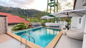 a swimming pool with chairs and an umbrella at Elephant Sports Bar and Accommodation in Phuket