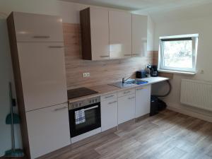 a kitchen with white cabinets and a sink at Ferienwohnung Nr 2 am Hambach in Falkenbach