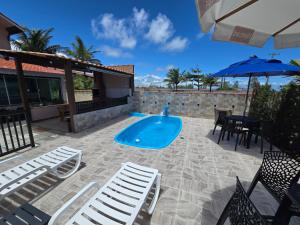 a patio with a swimming pool and chairs and an umbrella at Pousada Mar e Luz in Ilha Comprida