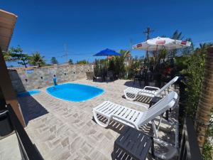 a patio with chairs and an umbrella and a pool at Pousada Mar e Luz in Ilha Comprida