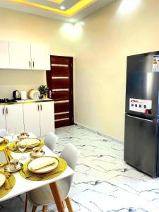 a kitchen with a table with plates and a refrigerator at Eden- Jacuzzi Privé et Terasse à 5mn de la plage in Dakar