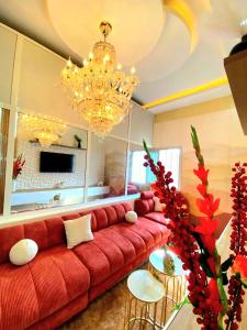 a living room with a red couch and a chandelier at Eden- Jacuzzi Privé et Terasse à 5mn de la plage in Dakar