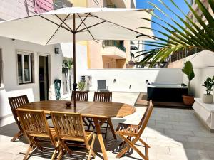 a wooden table and chairs with an umbrella on a patio at Miguel Surf House in Costa da Caparica
