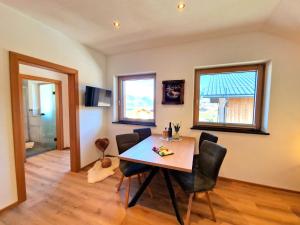 Un comedor con mesa y sillas y dos ventanas. en Apartment Wildschütz by Interhome, en Pill