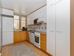 a kitchen with white appliances and wooden cabinets at Holiday Home Rantala 2 by Interhome in Ranua