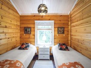 two beds in a room with wooden walls at Holiday Home Villa white water by Interhome in Kainuu