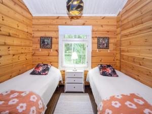 two beds in a room with wooden walls at Holiday Home Villa white water by Interhome in Kainuu
