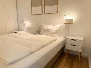 een slaapkamer met een wit bed en een nachtkastje bij Neu! Hirschgrund 10 OG Panorama, Sauna, Pool in Braunlage