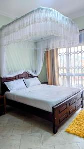 a bed with a canopy in a room with a window at NL Josephine's Apartment in Kampala