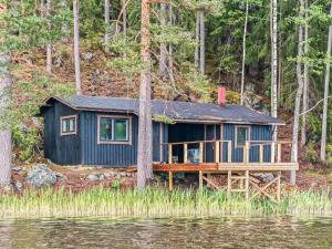 a blue house on a dock next to a body of water at Holiday Home Louhikko by Interhome in Houhajärvi