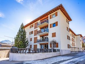 Un edificio de apartamentos con un árbol delante. en Apartment Chesa Promulins by Interhome, en Samedan