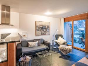 una sala de estar con un sofá y una silla en Apartment Chesa Promulins by Interhome, en Samedan